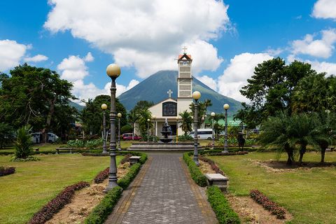 The town of La Fortuna: a park pathway, church, and Arenal Volcano in the background.